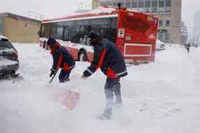 Des employés de la Commission de transport de Toronto tentent de dégager une chaussée alors qu'un bus est bloqué depuis les premières heures du matin à Toronto après qu'un blizzard majeur a déversé jusqu'à 60 cm de neige sur certaines parties du sud de l'Ontario, fermant les principales autoroutes et routes, à Toronto, le 17 janvier. , 2022.