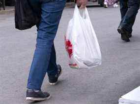 Une femme transporte un sac en plastique dans un marché de Montréal.