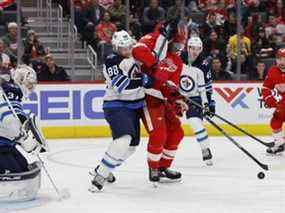 Le défenseur des Jets de Winnipeg Nate Schmidt et l'ailier droit des Red Wings de Détroit Givani Smith se battent pour la rondelle devant le gardien Connor Hellebuyck au Little Caesars Arena jeudi.  USA AUJOURD'HUI Sports