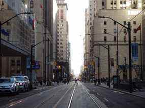 Les piétons traversent l'intersection de Bay Street et Wellington Street West dans le quartier financier de Toronto.