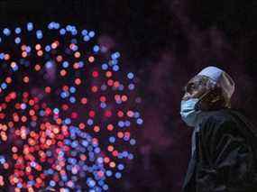 Un homme regarde des feux d'artifice illuminer le ciel au-dessus du port de Sydney alors que l'horloge sonne minuit le 1er janvier 2022 à Sydney, en Australie.