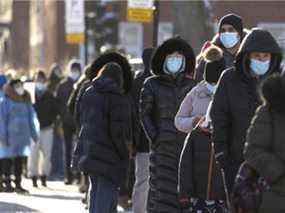 Des gens font la queue sur un site de vaccination et de dépistage de la COVID dans le quartier Saint-Henri de Montréal, le lundi 3 janvier 2022.