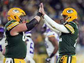 Le quart-arrière Aaron Rodgers des Packers de Green Bay (à droite) est félicité par le centre Lucas Patrick après un touché au cours du quatrième quart du match de leur équipe contre les Vikings du Minnesota au Lambeau Field le 2 janvier 2022 à Green Bay, Wisconsin.