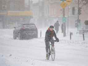 Une femme fait du vélo lors d'une chute de neige à Montréal, au Québec, le 17 janvier 2022. Le temps glacial devrait se maintenir, car l'air le plus froid depuis des années balaie l'Ontario et le Québec.