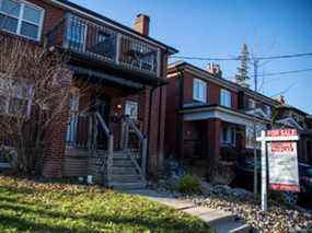 Un panneau à vendre est affiché à l'extérieur d'une maison à Toronto.