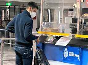 Le joueur de tennis serbe Novak Djokovic se tient devant un stand de l'Australian Border Force à l'aéroport de Melbourne, Australie, le 5 janvier 2022.