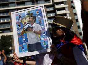 Un supporter de Novak Djokovic tient sa photo lors d'un rassemblement devant le Park Hotel, où la star du tennis serait détenue pendant son séjour en Australie, à Melbourne, le dimanche 9 janvier 2022.