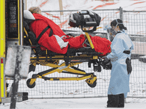 Des ambulanciers paramédicaux transfèrent un patient d'une ambulance à un hôpital de Montréal sur cette photo du 9 janvier 2022.  Le Québec cherche maintenant à facturer des frais supplémentaires aux résidents pour les soins de santé en guise de punition pour ne pas avoir reçu le vaccin COVID-19.