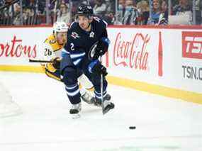 Le défenseur des Jets de Winnipeg Dylan DeMelo (2) s'éloigne de l'attaquant des Predators de Nashville Philip Tomasino (26) au cours de la première période au Centre Canada Vie à Winnipeg le 23 octobre 2021.