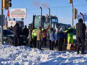 Des partisans sur la route transcanadienne à l'ouest de Winnipeg encouragent les camionneurs du Freedom Convoy qui se dirige vers Ottawa pour protester contre le mandat fédéral de vaccination contre la COVID-19 pour les camionneurs, le 25 janvier 2022.