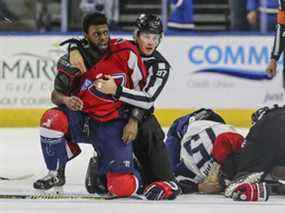 Le défenseur des Stingrays de Caroline du Sud, Jordan Subban, à gauche, est retenu par un juge de ligne après s'être battu avec le défenseur des Icemen de Jacksonville, Jacob Panetta, samedi.  La ECHL a suspendu Panetta après que Subban l'ait accusé d'avoir fait un geste raciste.