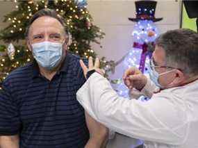 Le premier ministre François Legault reçoit un vaccin de rappel COVID-19 de Georges Nader au Stade olympique le 27 décembre 2021.