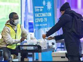 Un homme se désinfecte les mains avant de recevoir un nouveau masque au centre de vaccination COVID-19 du Palais des congrès de Montréal le jeudi 20 janvier 2022.