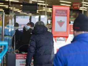 Les acheteurs font la queue pour montrer leur passeport de vaccination dans un magasin Canadian Tire à Montréal.