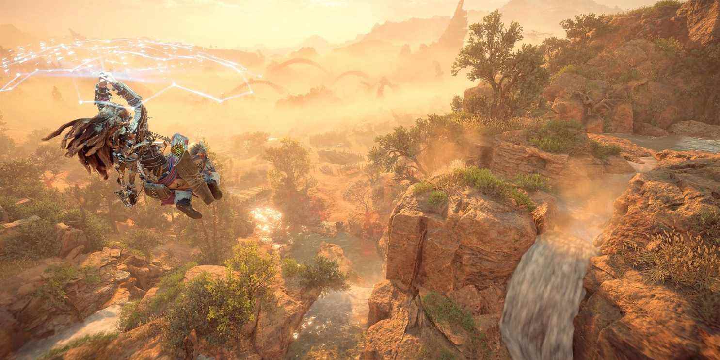 aloy glisse sous un bouclier bleu brillant devant une série de chutes d'eau 