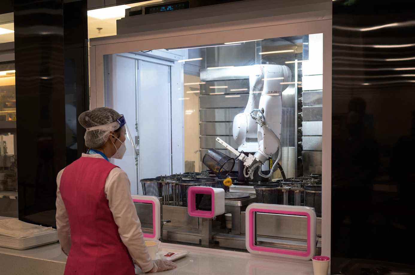 Un ouvrier attend un robot traitant une commande dans la salle à manger du Centre de presse principal avant les Jeux olympiques d'hiver de 2022 à Pékin, le 28 janvier 2022. (Photo de Fabrice COFFRINI / AFP) (Photo de FABRICE COFFRINI/AFP via Getty Images)