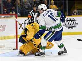 Le centre des Canucks de Vancouver Matthew Highmore (15 ans) marque un but contre le gardien de but des Nashville Predators Juuse Saros (74 ans) lors de la première période d'un match de hockey de la LNH le mardi 1er février 2022 à Nashville, Tennessee.