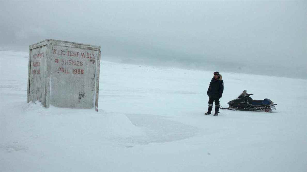 Un homme debout devant un conteneur blanc au milieu de la toundra antarctique dans The Last Winter.