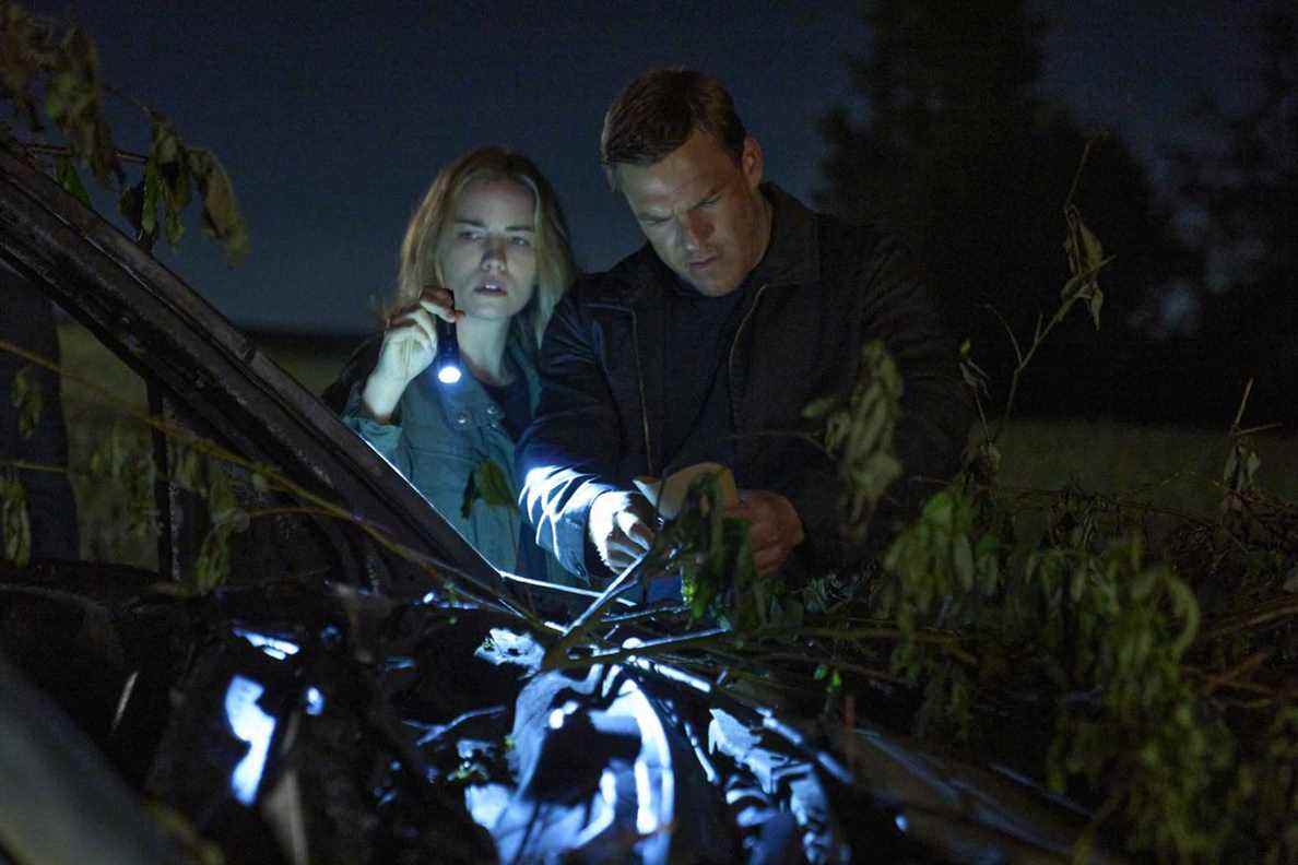 Jack Reacher, un homme de grande taille portant un pull à col, enquête dans les bois avec une policière blonde (tenant une lampe de poche).