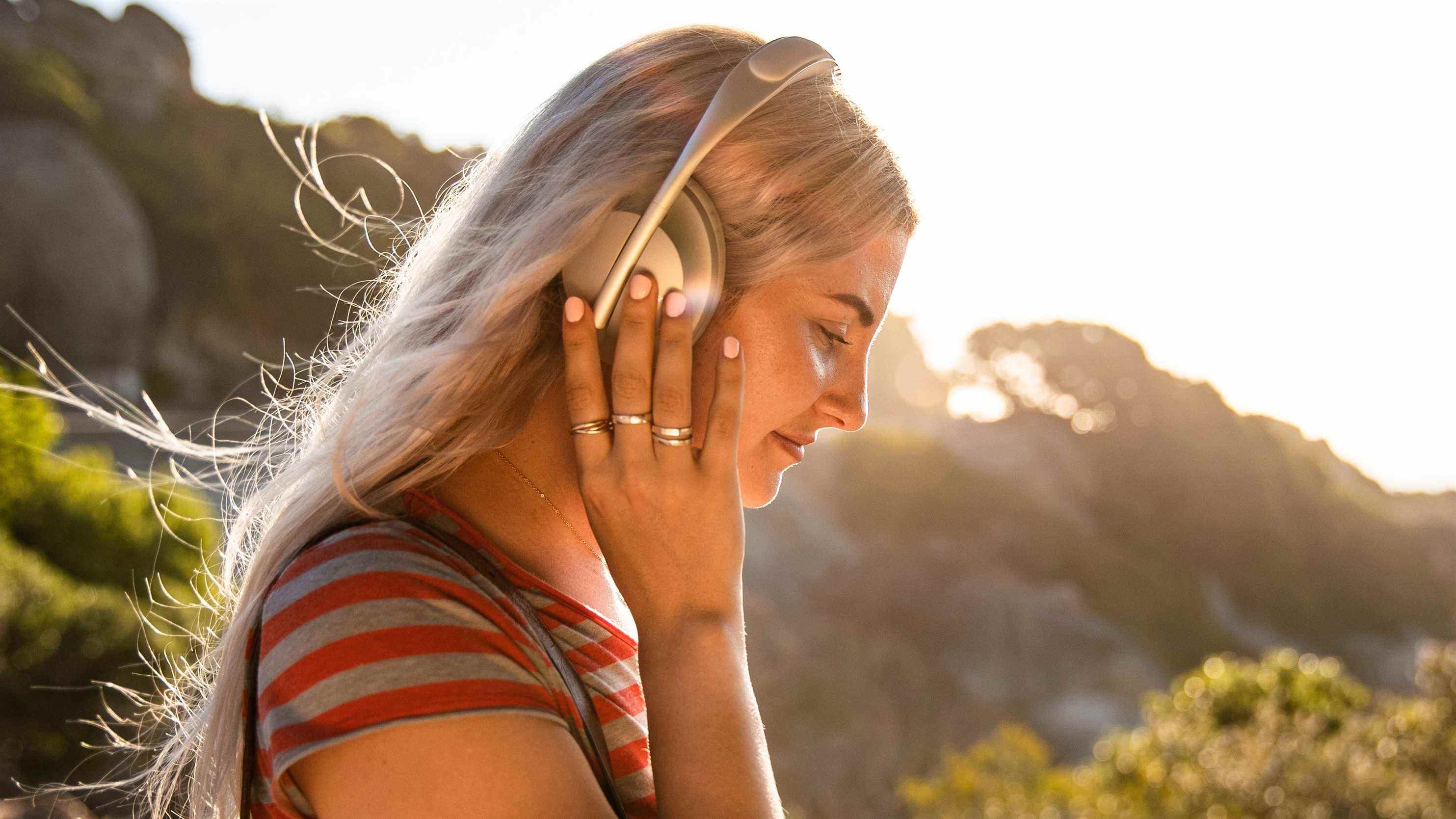 Une femme portant le casque antibruit bose 700 casque à l'extérieur par une journée ensoleillée