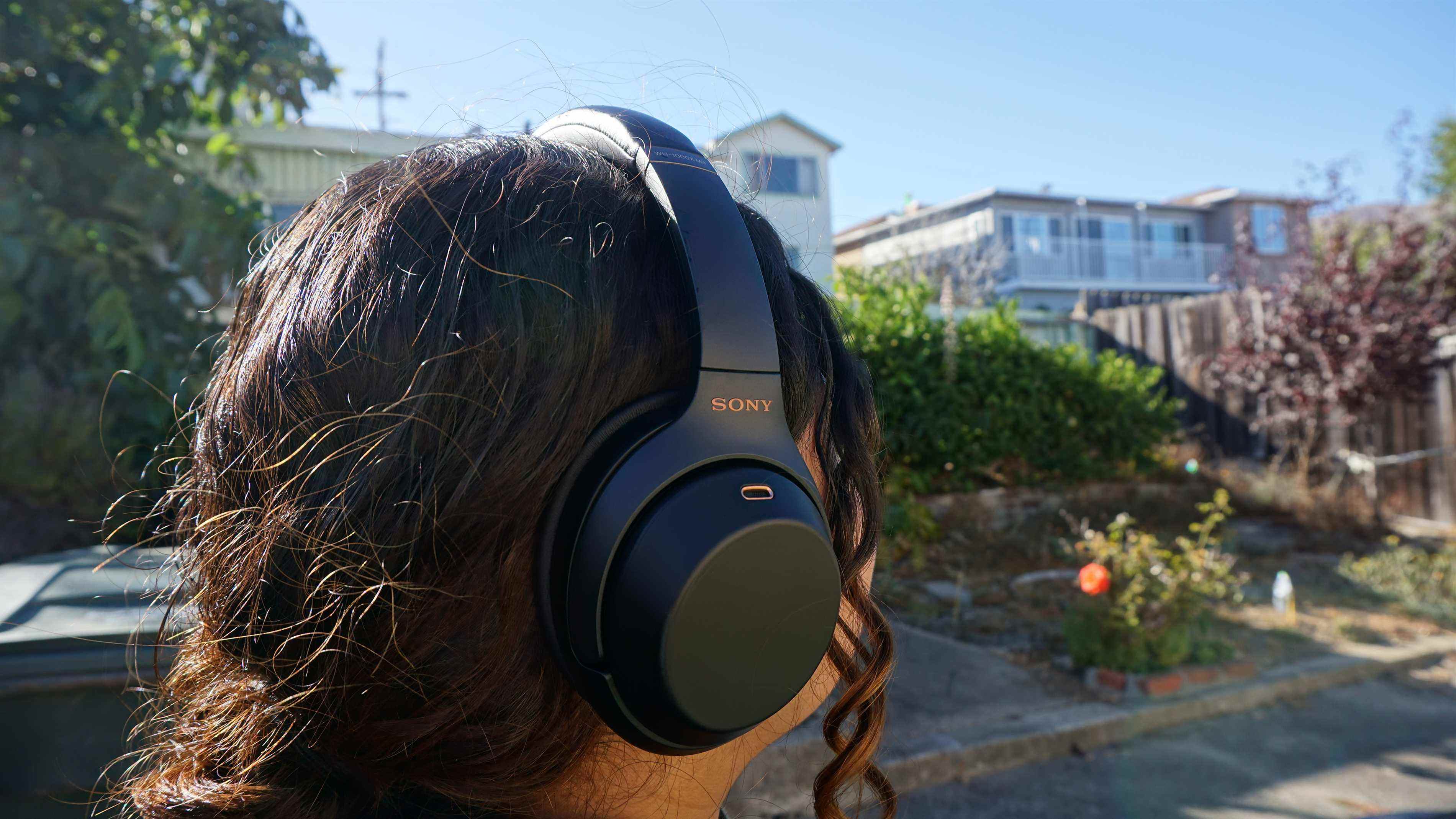 Quelqu'un portant le casque Sony WH-1000XM3 à l'extérieur par une journée ensoleillée