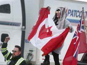 Des manifestants anti-mandat agitent des drapeaux et des pancartes canadiens sur Huron Church Road en direction sud le lundi 7 février 2022.