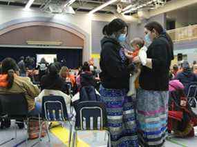 Pauline Pelly, à l'extrême droite, tient sa fille Ella lors d'un événement public au gymnase de l'école Keeseekoose de la Première Nation de Keeseekoose le mardi 15 février 2022. L'événement a révélé que 54 tombes ont été découvertes grâce à un géoradar sur le site de l'ancien pensionnats St. Philip's et Fort Pelly.