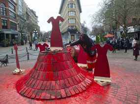 Lisa-Marie Gisle laisse une offrande et brûle de la sauge sur la statue de Gassy Jack dans les rues Carrall et Water à Vancouver le 14 février 2022, après qu'elle a été démolie et vandalisée lors de la Marche commémorative des femmes.