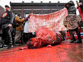 Les partisans démontent la statue de Gassy Jack et la recouvrent de peinture rouge lors de la 31e marche commémorative annuelle des femmes, en l'honneur des femmes et des filles autochtones disparues et assassinées dans le quartier Downtown Eastside, à Vancouver, le 14 février 2022.