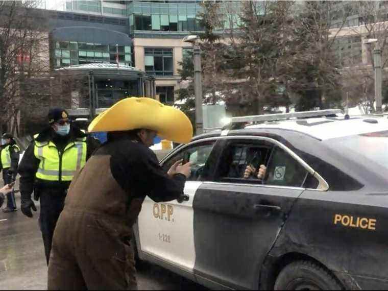 Un agent de la Police provinciale de l’Ontario permet aux manifestants d’Ottawa de prendre des photos dans sa voiture de patrouille, des émissions vidéo