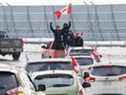 Jeudi, des personnes brandissant des drapeaux canadiens manifestent à l'aéroport international d'Ottawa. 