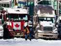 Un homme pellette près de camions qui restent sur la rue Rideau, dans le cadre de l'occupation en cours d'Ottawa, le 18 février.