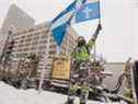 Un manifestant agite un drapeau du Québec devant l'Assemblée nationale à Québec le samedi 19 février 2022.  