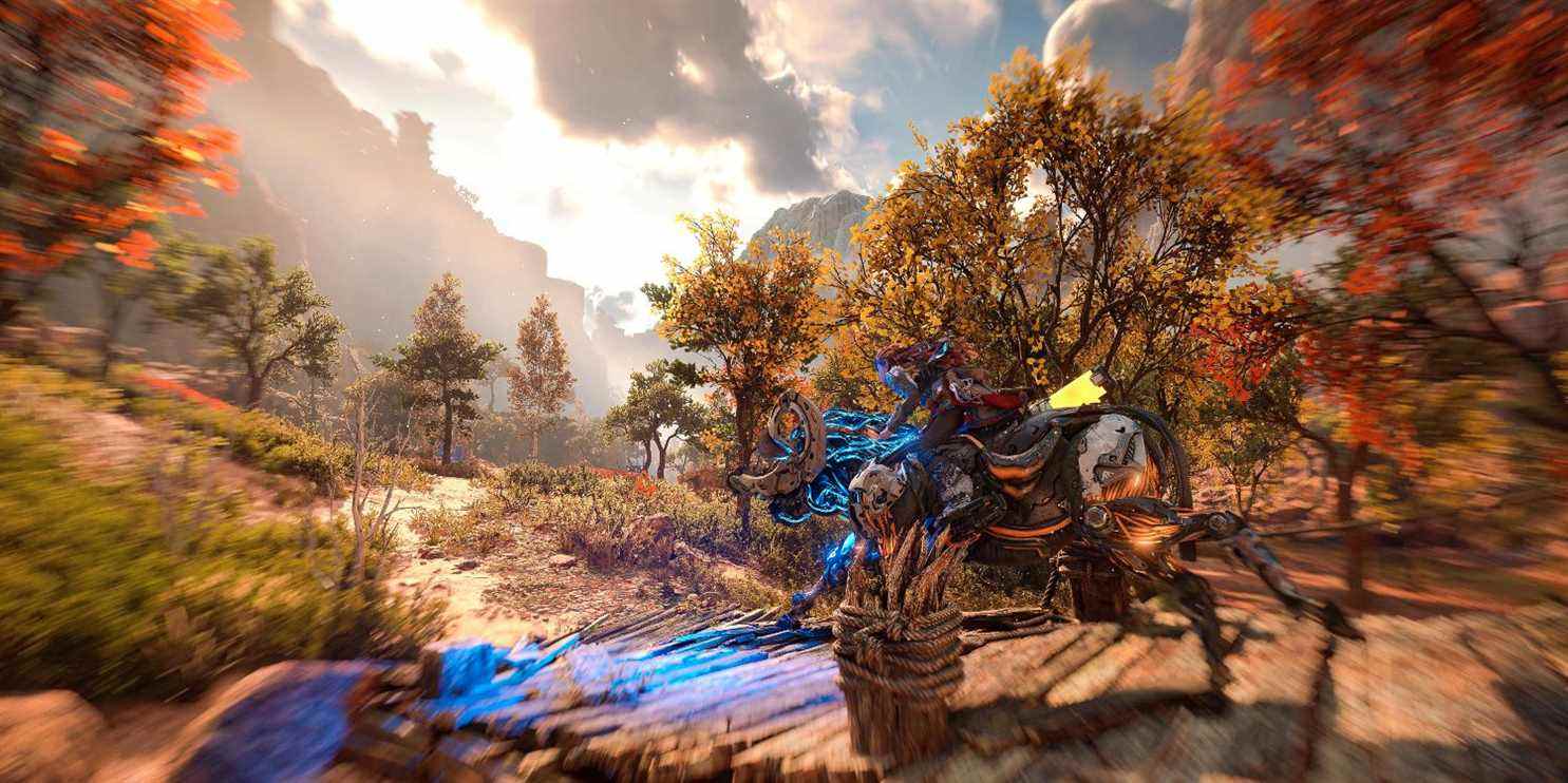 aloy sur un chargeur roulant sur un petit pont en bois flanqué d'arbres aux feuilles orange et rouge 