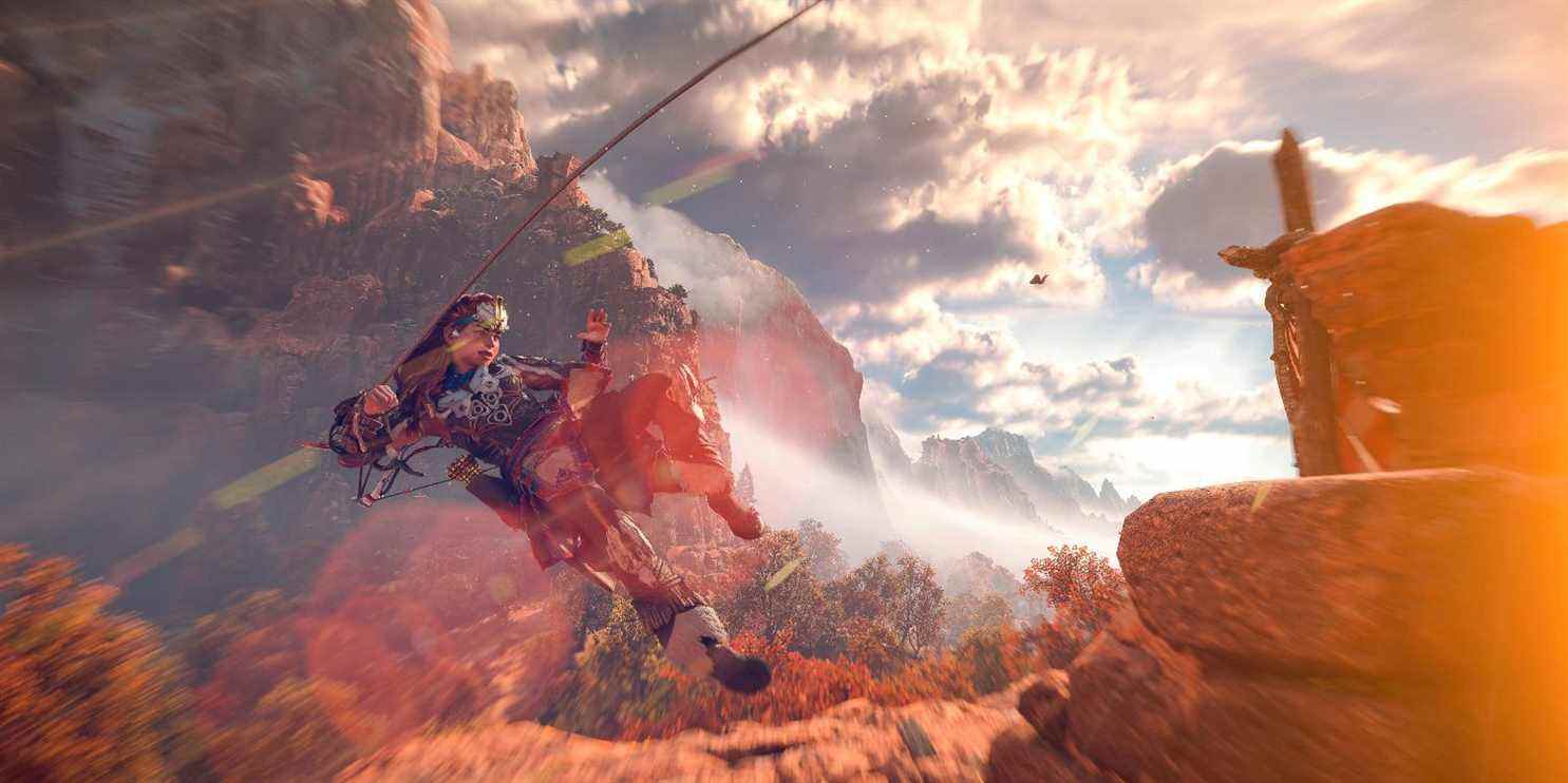 aloy utilise l'outil de corde pullcaster pour voler dans les airs avec des montagnes derrière elle