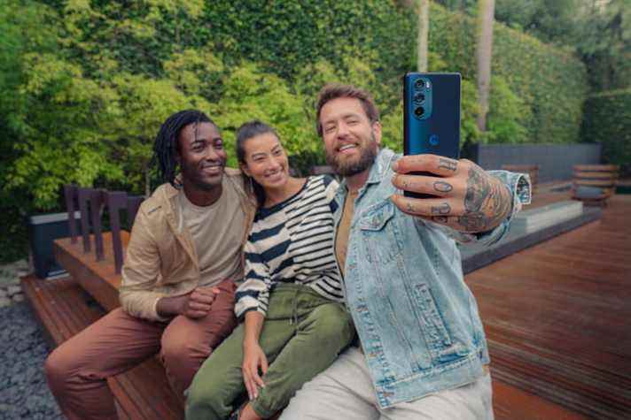 Un homme prend un selfie avec des amis à l'aide d'un smartphone Motorola Edge Plus 2022.