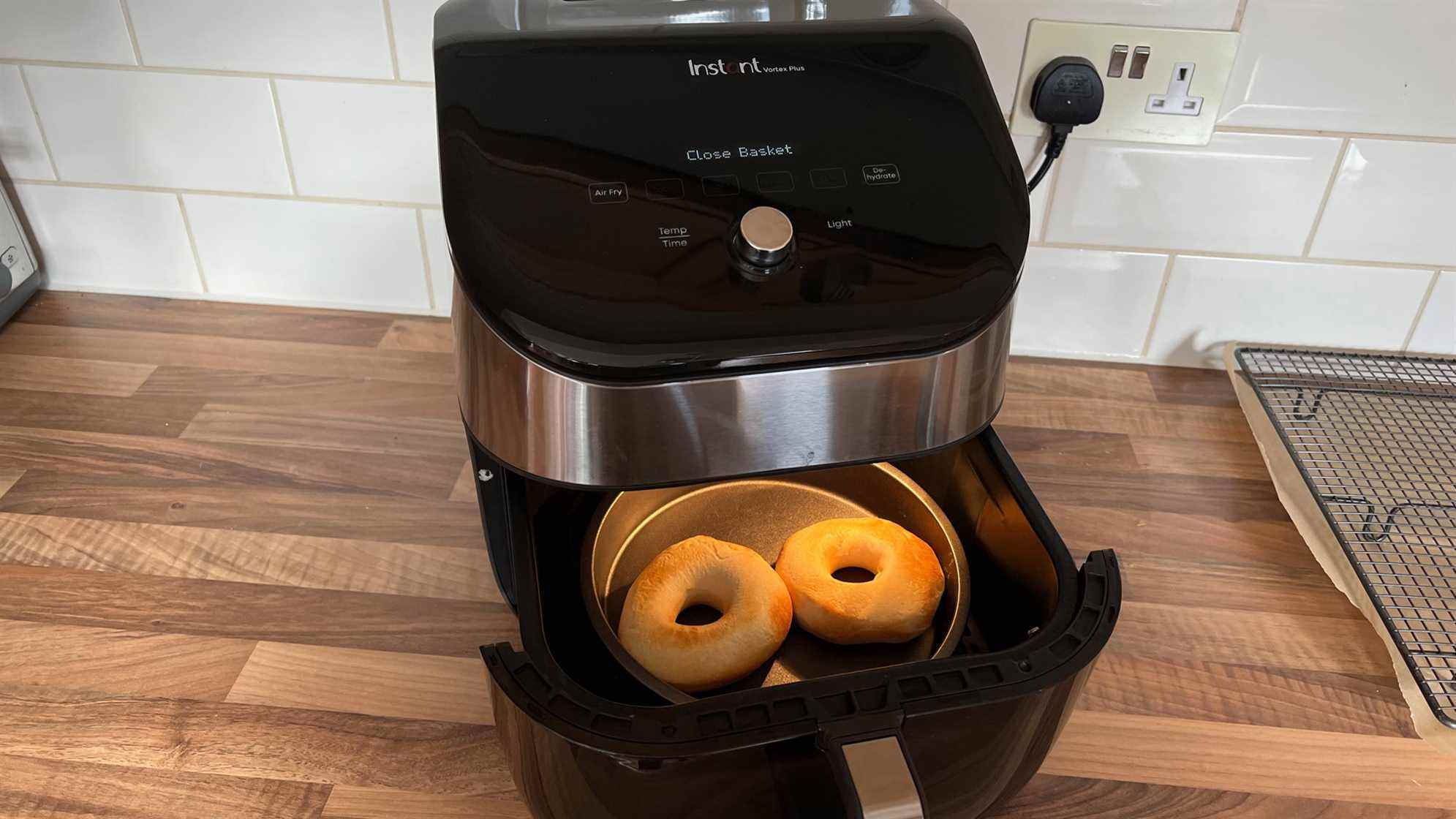 Deux beignets dans une boîte métallique dans le panier d'une friteuse à air, à mi-cuisson