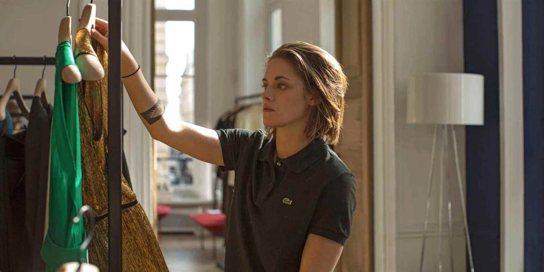 Kristen Stewart as Maureen holding up clothes in Personal Shopper