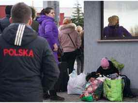 Un enfant est assis parmi ses effets personnels alors que des réfugiés ukrainiens traversent la frontière entre l'Ukraine et la Pologne au poste frontière de Korczowa-Krakovets, en Pologne, le 26 février 2022.