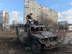 Un combattant ukrainien de la Défense territoriale examine un véhicule de mobilité d'infanterie russe GAZ Tigr détruit après le combat à Kharkiv dimanche.  L'artillerie russe a bombardé aujourd'hui des quartiers résidentiels de la deuxième plus grande ville d'Ukraine, tuant peut-être des dizaines de personnes, ont déclaré des responsables ukrainiens.