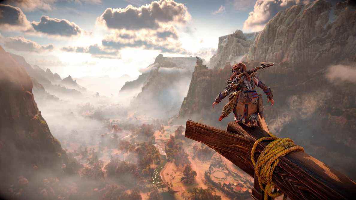 Aloy perché sur une poutre en bois au-dessus d'une vallée fluviale brumeuse dans Horizon Forbidden West sur PS5