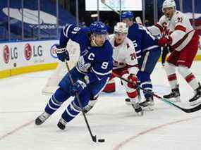 L'attaquant des Maple Leafs de Toronto John Tavares contrôle la rondelle contre l'attaquant des Hurricanes de la Caroline Sebastian Aho lors de la première période au Scotiabank Arena de Toronto, le 7 février 2022.