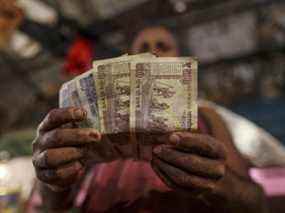 Un vendeur affiche des billets indiens de cinq cents, cent cinquante roupies pour photographier sur un marché de gros de légumes à Mumbai, en Inde.