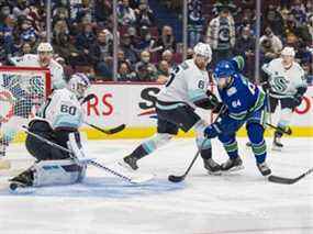 Le défenseur du Kraken de Seattle Adam Larsson (6) regarde l'attaquant des Canucks de Vancouver Tyler Motte (64) marquer contre le gardien Chris Driedger (60) en première période au Rogers Arena.