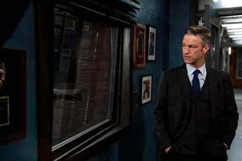 peter scanavino, jouant sonny carisi, regarde à travers une fenêtre intérieure en verre dans une scène de la loi et de l'ordre svu