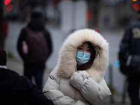 Une personne emmitouflée dans une veste épaisse pour le temps froid porte un masque facial pour freiner la propagation du COVID-19 à Vancouver.