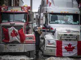 Une femme accueille un chauffeur de camion dans les rues bordées de véhicules du centre-ville le dimanche 6 février 2022, lors de la manifestation du Freedom Convoy.