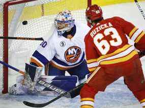 Le gardien de but des Islanders de New York Ilya Sorokin regarde en arrière alors que l'attaquant des Flames de Calgary Adam Ruzicka marque au Scotiabank Saddledome de Calgary le samedi 13 février 2022.