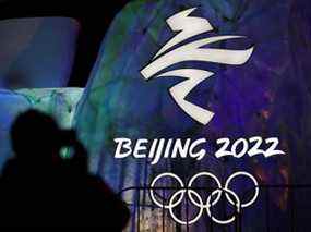 Un homme photographie un logo illuminé pour les Jeux olympiques d'hiver de 2022 à Pékin, en Chine.  Les Jeux, auxquels une majorité de Canadiens ont déclaré que le Canada ne devrait pas participer, débuteront le 4 février.