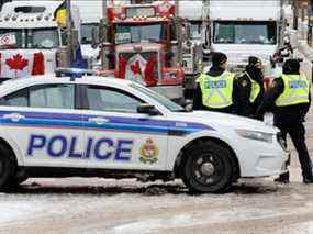 La police patrouille une barricade tandis que des véhicules bloquent les rues du centre-ville alors que les camionneurs et les partisans continuent de protester contre les mandats de vaccination contre la maladie à coronavirus (COVID-19) à Ottawa, Ontario, Canada, le 3 février 2022.